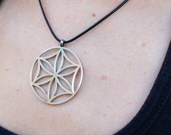 May include: A silver pendant necklace with a geometric flower of life design. The necklace is on a black cord.