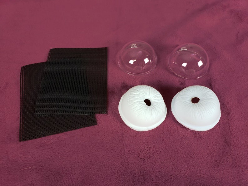Puede incluir: Dos moldes de pl&aacute;stico transparente en forma de c&uacute;pula, dos moldes de ojos de pl&aacute;stico blanco y dos cuadrados de malla negra.