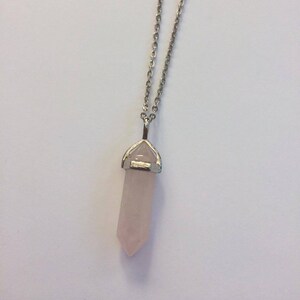 May include: A silver chain necklace with a rose quartz crystal pendant. The crystal is shaped like a point and is set in a silver bezel.