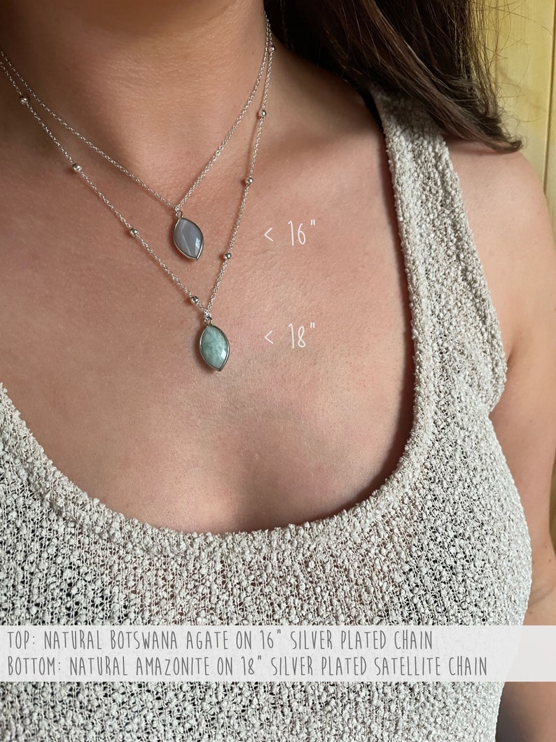 May include: Two silver necklaces with gemstone pendants. The top necklace features a Botswana agate pendant on a 16-inch chain. The bottom necklace has an amazonite pendant on an 18-inch chain. Both necklaces are silver-plated.