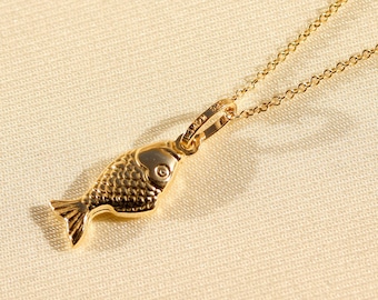 May include: A gold chain necklace with a small, detailed fish pendant.