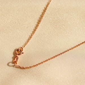 May include: A close-up of a rose gold chain necklace with a lobster clasp.