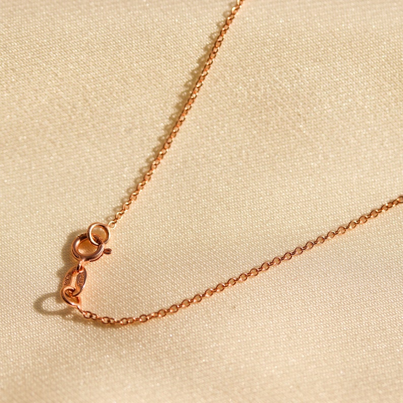 May include: A close-up of a rose gold chain necklace with a lobster clasp.