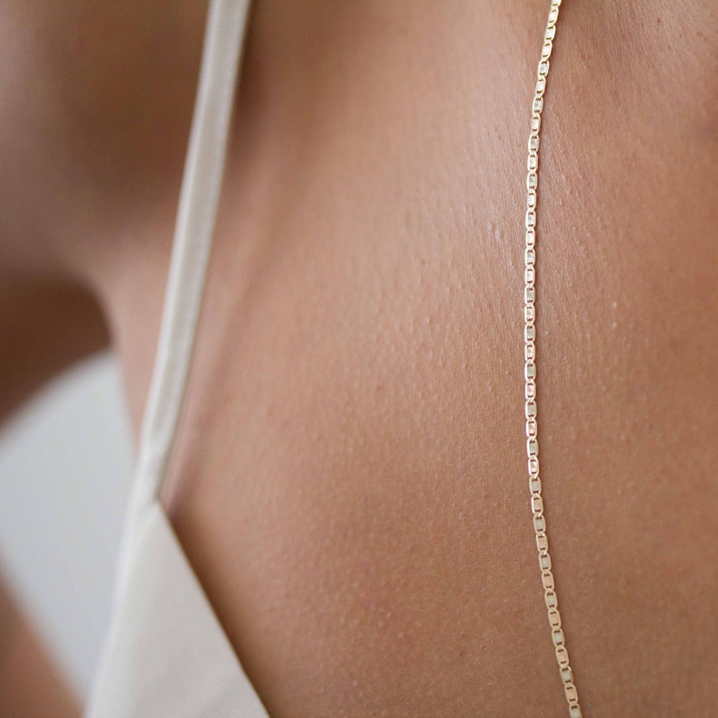May include: A gold chain necklace with a box chain style. The chain is on a person's neck and is visible against their skin.