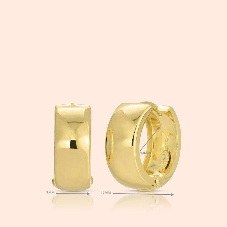 May include: A pair of gold hoop earrings with a smooth, rounded surface. The earrings measure 1.7 inches in diameter and 0.7 inches in width.