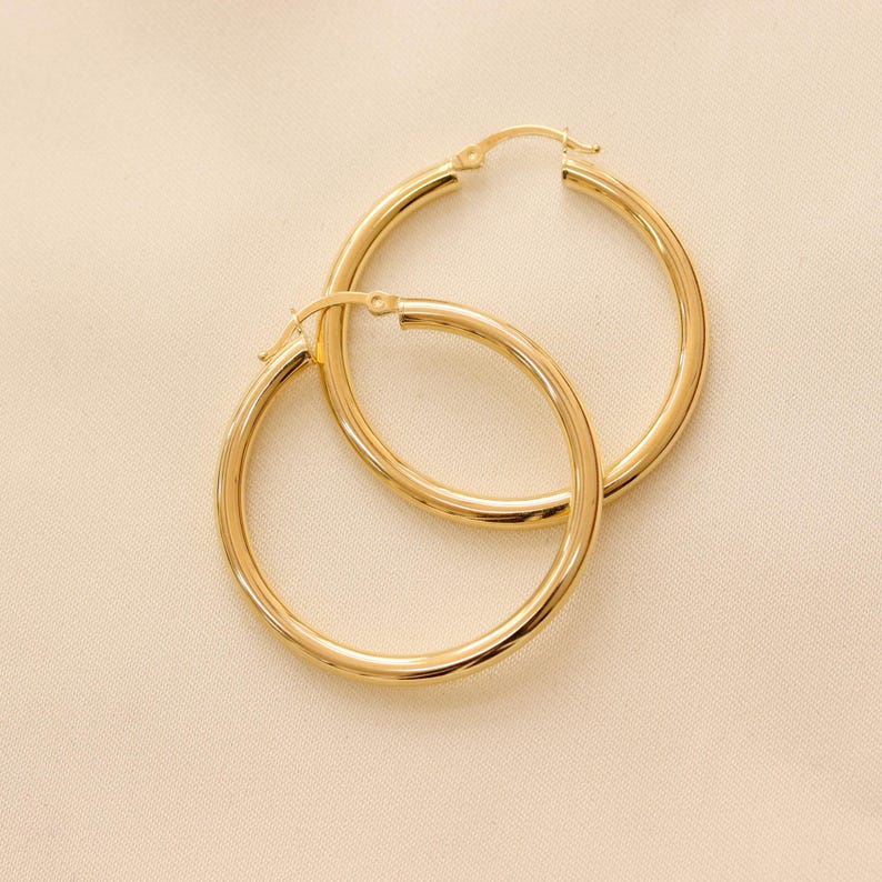 May include: A pair of gold hoop earrings. The earrings are simple and elegant, with a smooth, polished finish.