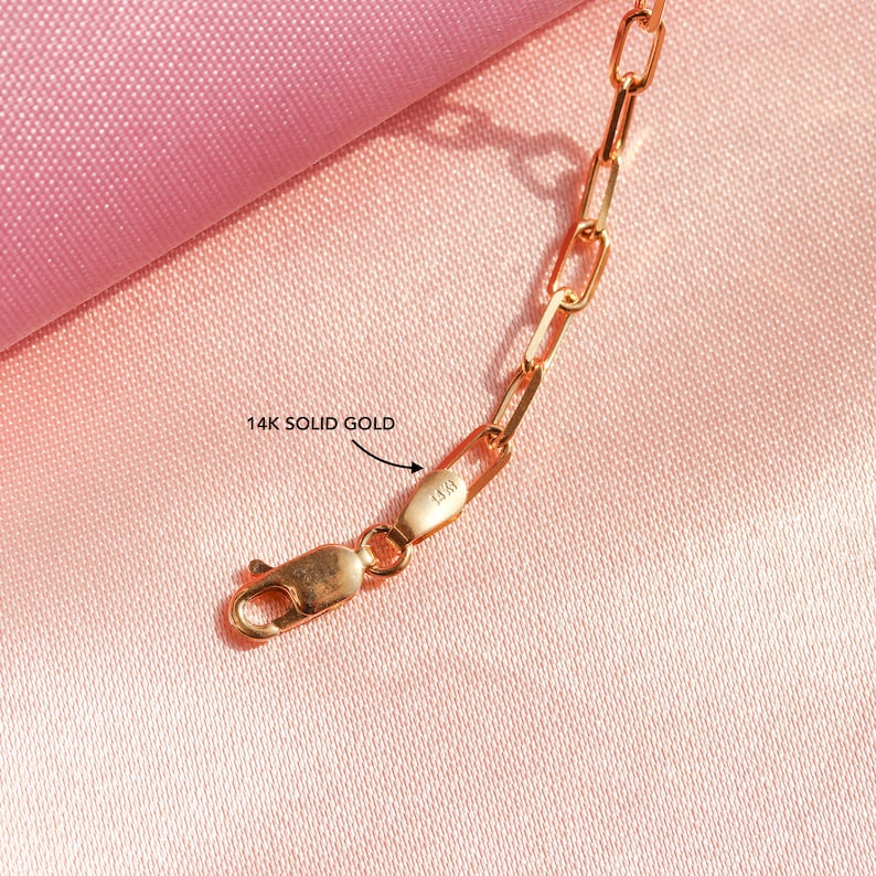May include: Close-up of a gold chain necklace with a clasp. The clasp is marked "14K" indicating it is made of 14 karat gold.