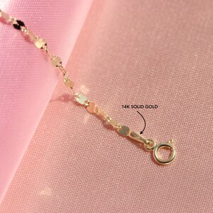 May include: A gold chain necklace with a 14k solid gold clasp. The chain is made of small, round links.