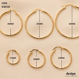 May include: Six pairs of gold hoop earrings in different sizes. The earrings are 2 mm wide and range in diameter from 15 mm to 40 mm. The earrings are labeled with their diameter in millimeters.