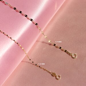 May include: Two gold chains with a delicate, flat, oval-shaped link. The chain on the top is 1.9 mm wide and the chain on the bottom is 1.5 mm wide.