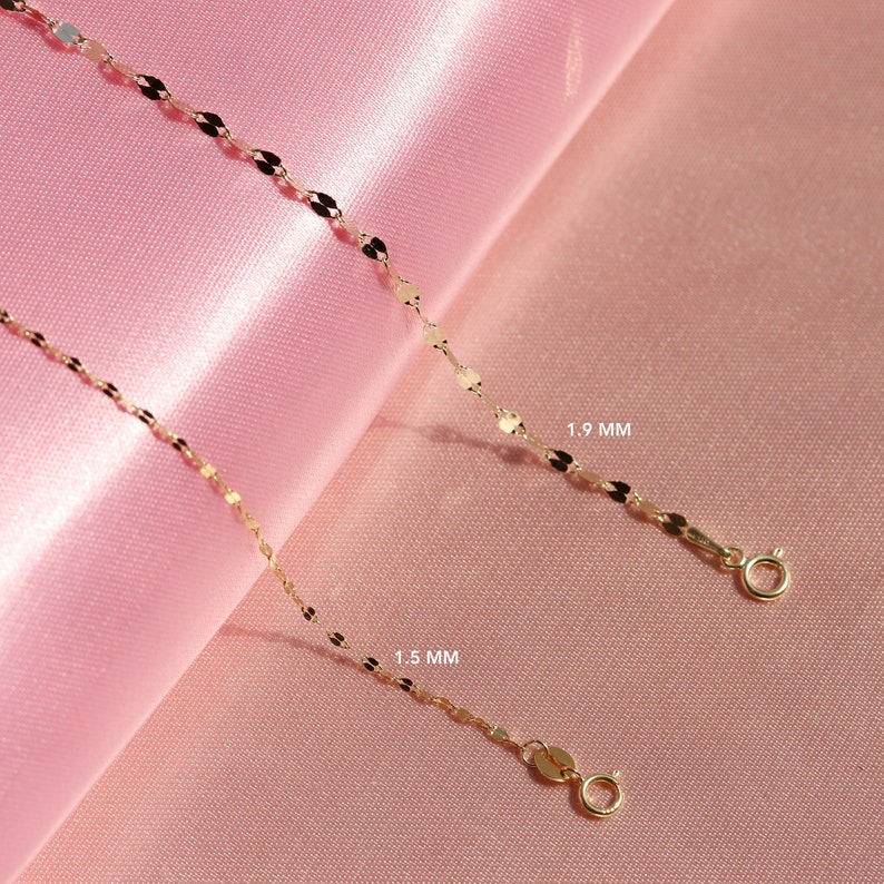 May include: Two gold chains with a delicate, flat, oval-shaped link. The chain on the top is 1.9 mm wide and the chain on the bottom is 1.5 mm wide.