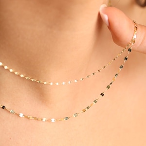 Puede incluir: Un delicado collar de cadena de oro con un dise&ntilde;o en capas. La cadena est&aacute; hecha de peque&ntilde;os eslabones ovalados.