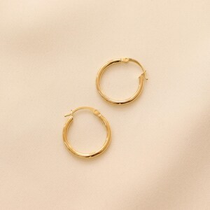 May include: A pair of gold hoop earrings. The earrings are simple and classic, and they would make a great addition to any jewelry collection.