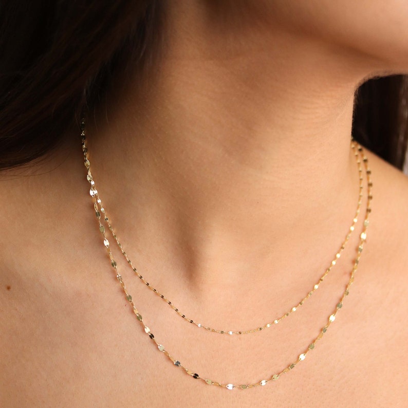 Puede incluir: Un delicado collar de cadena de oro con un dise&ntilde;o en capas. La cadena est&aacute; hecha de peque&ntilde;os eslabones ovalados planos.