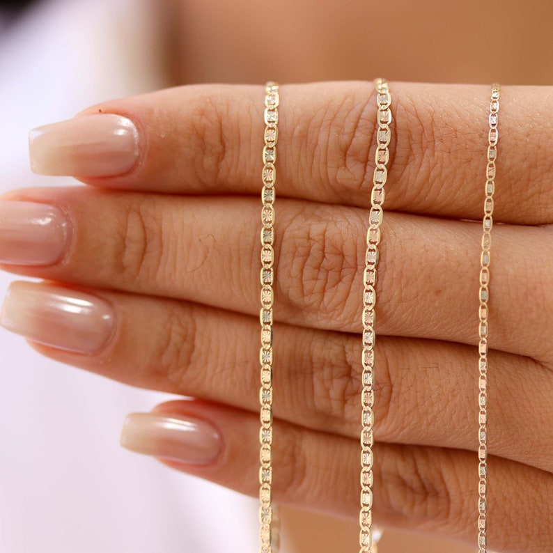May include: Three gold chains of different lengths and widths. The chains are made of a combination of yellow, white, and rose gold.