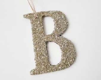 May include: Gold glitter letter B ornament with a twine hanger.