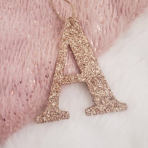 May include: A gold glitter letter A ornament with a twine string for hanging.