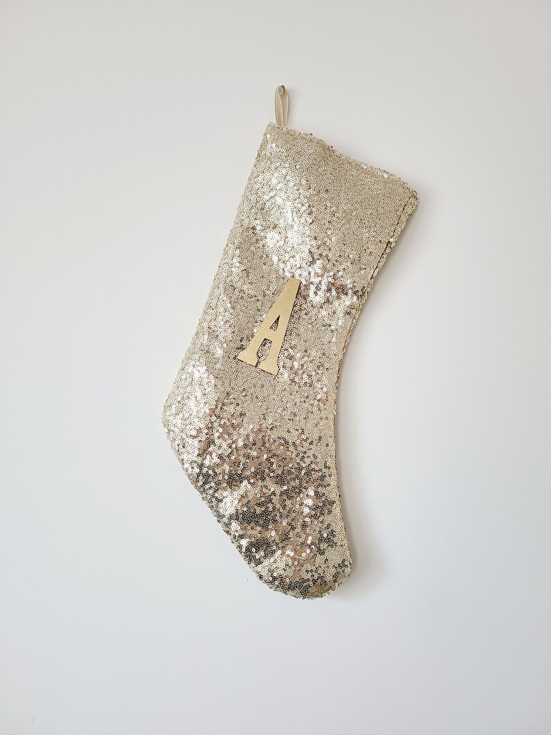 May include: Gold sequin Christmas stocking with a wooden letter A attached to the front.
