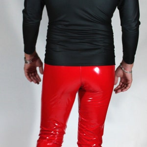 May include: A person wearing a black long-sleeved shirt and red patent leather pants. The person is walking towards the camera.
