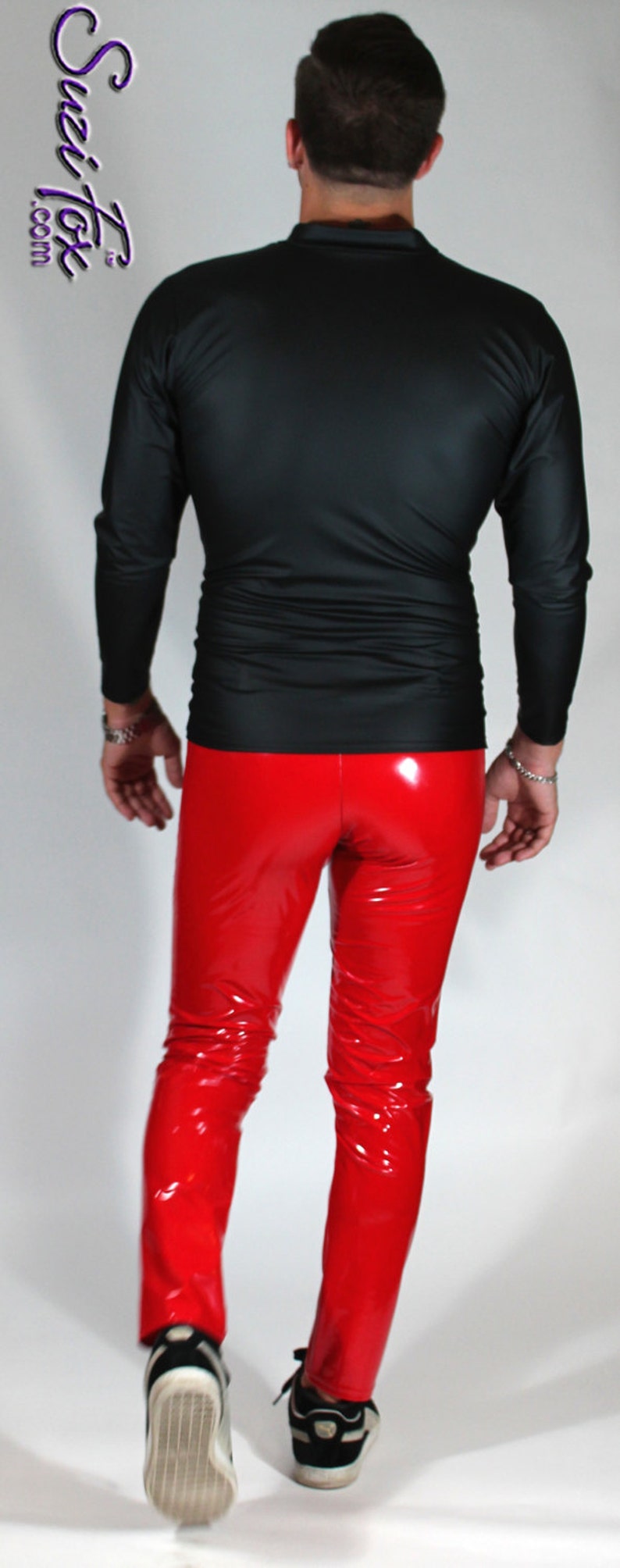 May include: A person wearing a black long-sleeved shirt and red patent leather pants. The person is walking towards the camera.