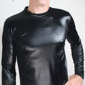 May include: A black long-sleeved shirt with a shiny, satin-like finish. The shirt has a crew neck and is worn over silver snake-skin patterned pants.