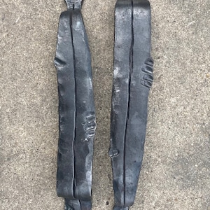 May include: Two handcrafted, black metal fish-shaped door pulls. Each pull features a textured, elongated body with details suggesting fins and a head. The pulls are designed to be mounted on a door or cabinet, adding a rustic touch.