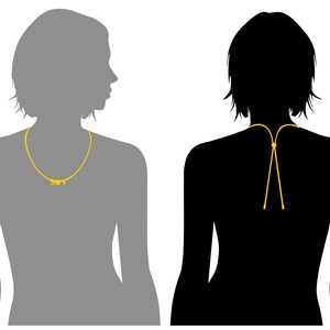 K&ouml;nnte beinhalten: Zwei Silhouetten von Personen, die eine goldene Halskette tragen. Die Halskette ist eine einfache Kette mit einem kleinen Anh&auml;nger. Die Silhouette links ist nach rechts gerichtet, und die Silhouette rechts ist nach vorne gerichtet.