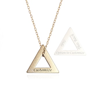 May include: Gold triangle necklace with a customizable inscription. The back of the triangle pendant is blank and can be engraved with a personalized message.