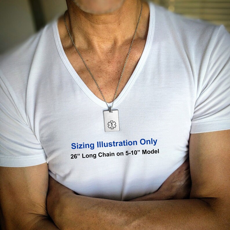 Op de afbeelding: Een zilveren ketting met een zilveren hanger met een medisch symbool. De ketting is 66 cm lang en wordt gedragen door een model. De tekst "Sizing Illustration Only 26" Long Chain on 5-10" Model" is gedrukt op het witte T-shirt dat het model draagt.
