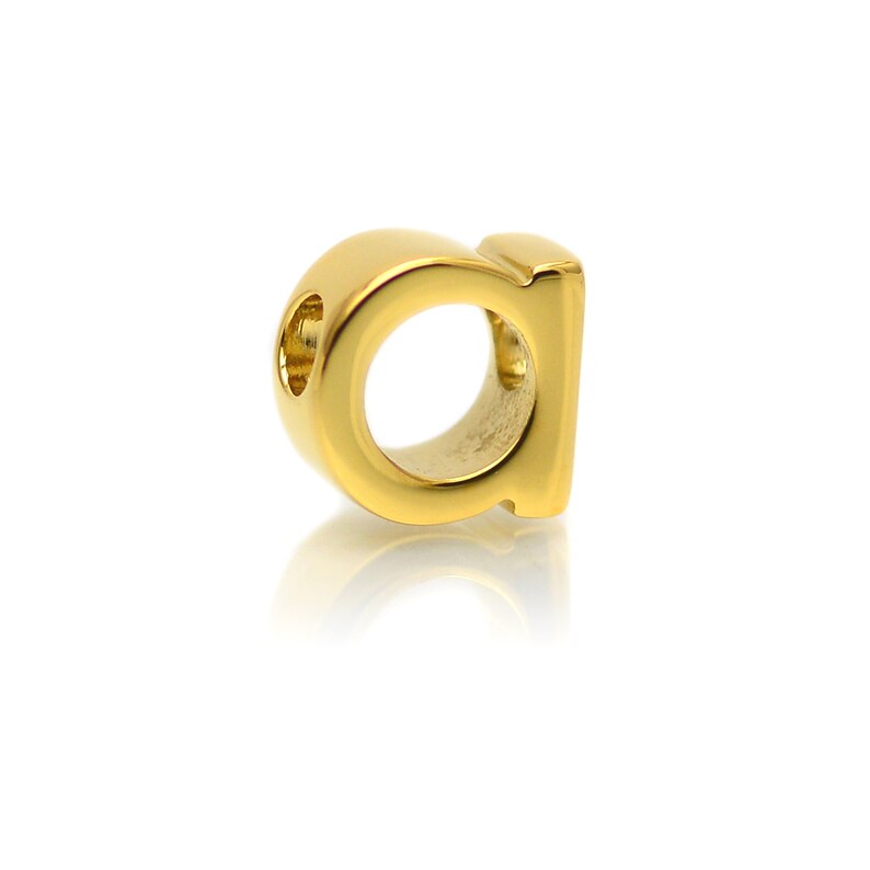 K&ouml;nnte beinhalten: Goldener 'a'-Anh&auml;nger mit einem Loch zum Einf&auml;deln in eine Halskette oder ein Armband.