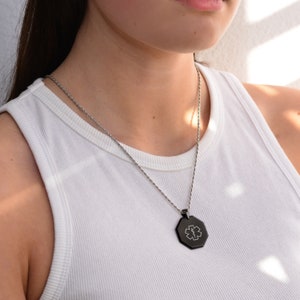 May include: A silver chain necklace with a black octagonal pendant featuring a medical symbol.