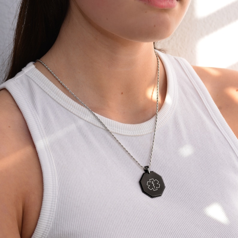 May include: A silver chain necklace with a black octagonal pendant featuring a medical symbol.