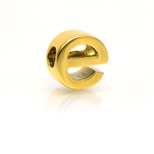 K&ouml;nnte beinhalten: Goldfarbener Metall-Anh&auml;nger in Form des Buchstabens 'e' mit einem Loch in der Mitte zum Einf&auml;deln auf eine Halskette oder ein Armband.