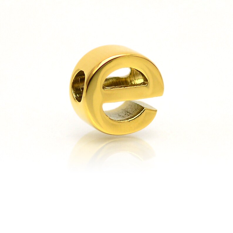K&ouml;nnte beinhalten: Goldfarbener Metall-Anh&auml;nger in Form des Buchstabens 'e' mit einem Loch in der Mitte zum Einf&auml;deln auf eine Halskette oder ein Armband.