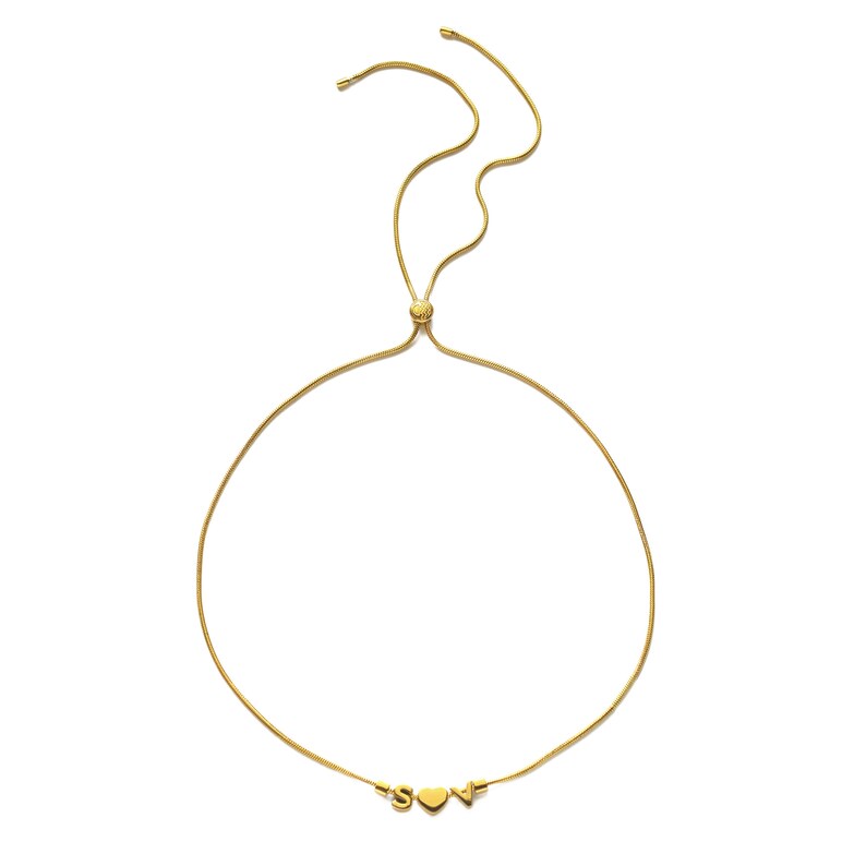 K&ouml;nnte beinhalten: Eine goldene Kettenkette mit einem Herz und den Buchstaben "S" und "V", die daran h&auml;ngen. Die Kette ist in der L&auml;nge verstellbar.