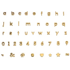 K&ouml;nnte beinhalten: Goldfarbene Metall-Anh&auml;nger in Form von Buchstaben und Zahlen, einschlie&szlig;lich Satzzeichen, einem Herz und Sternen.