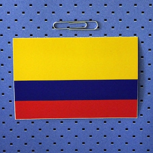 May include: A yellow, blue, and red flag with a paperclip on top. The flag is on a blue background with a grid pattern.