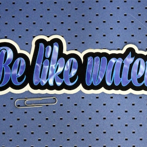 May include: A blue and black sticker with the text "Be like water" in a stylized font. The sticker has a water ripple pattern.