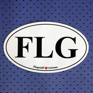 May include: White oval sticker with black text that reads "FLG" and the words "Flagstaff Arizona" with a red heart symbol between the words.