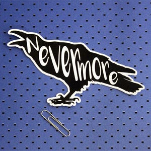 May include: Black silhouette of a raven with the word "Nevermore" written on its body. The raven is on a blue background with a repeating pattern of small squares.