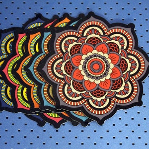 May include: A set of five colorful mandala stickers with intricate designs. The mandalas are layered on top of each other, creating a visually appealing pattern.