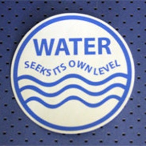 May include: White round sticker with a blue border. The sticker has the word "WATER" in large blue letters and the text "SEEKS ITS OWN LEVEL" in smaller blue letters. The sticker also has a blue wave design.