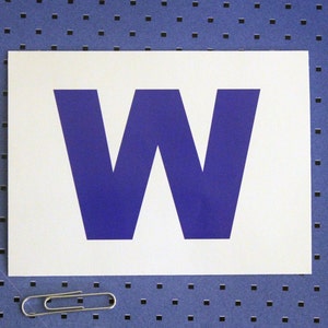 May include: A white card with the letter "W" printed in a bold, dark blue font.