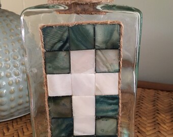 Green tinted triangular glass container with mother of pearl cross motif, jute trim and cork lid