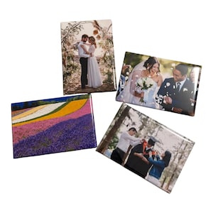 May include: Four rectangular photo magnets. One shows a couple embracing under an archway, another a bride and groom laughing, a third a field of colorful flowers, and the last a graduation ceremony.
