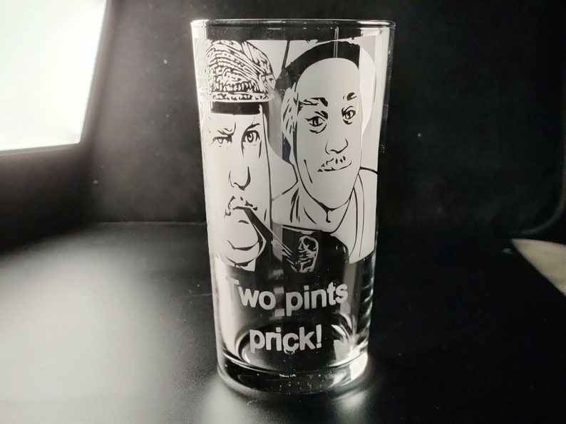 Puede incluir: Un vaso de vidrio transparente con una imagen grabada en blanco y negro de dos hombres. El texto "Two pints prick!" est&aacute; grabado en la parte inferior del vaso.
