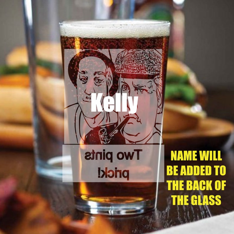 Puede incluir: Un vaso de pinta de vidrio transparente con una imagen en blanco y negro de dos hombres. El texto "Kelly" est&aacute; impreso en el vaso. El texto "Two pints!" est&aacute; impreso al rev&eacute;s en el vaso. El texto "NAME WILL BE ADDED TO THE BACK OF THE GLASS" est&aacute; impreso debajo del vaso.