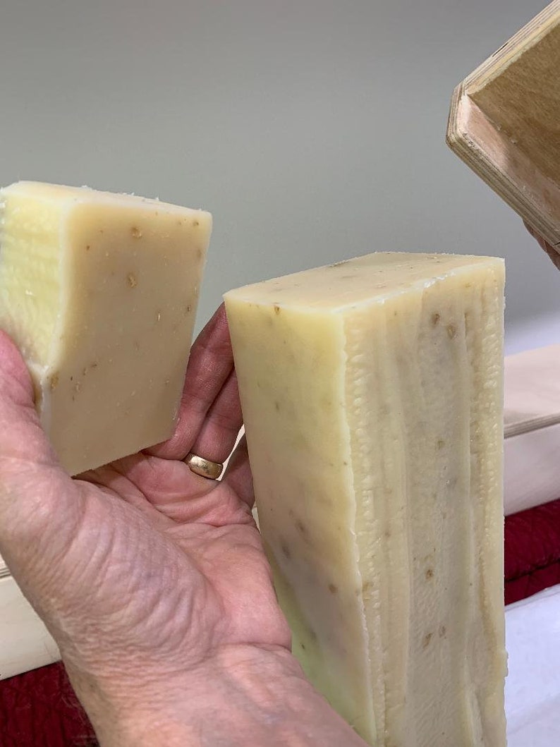 K&ouml;nnte beinhalten: Zwei handgemachte Seifenst&uuml;cke, eines ist ein kleineres St&uuml;ck und das andere ein gr&ouml;&szlig;eres St&uuml;ck. Beide St&uuml;cke sind hellbeige mit braunen Flecken.