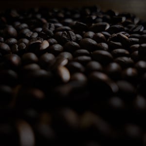 Può includere: Un'immagine ravvicinata di un grande mucchio di chicchi di caffè marroni scuri.