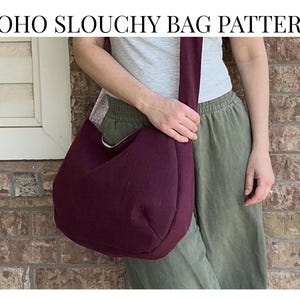 Könnte beinhalten: Eine bordeauxfarbene Boho-Schlauchbeutel-Tasche mit langem Riemen, gehalten von einer Person. Die Tasche ist aus weichem Material und hat eine runde Form. Der Text auf dem Bild lautet "BOHO SLOUCHY BAG PATTERN, NO ZIPPER, BEGINNER."